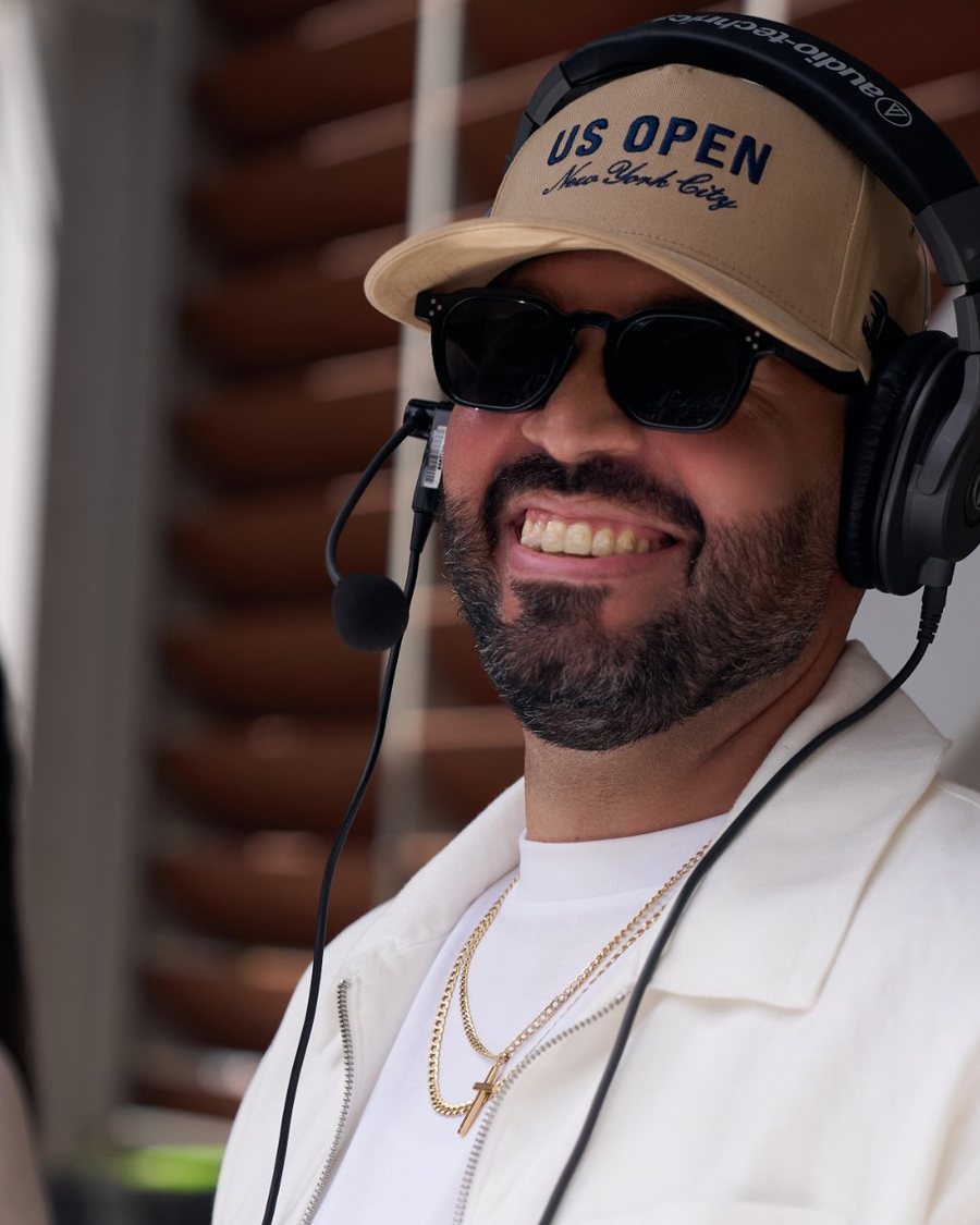 DJ Mode grinning in a US Open cap, headphones and headset mic