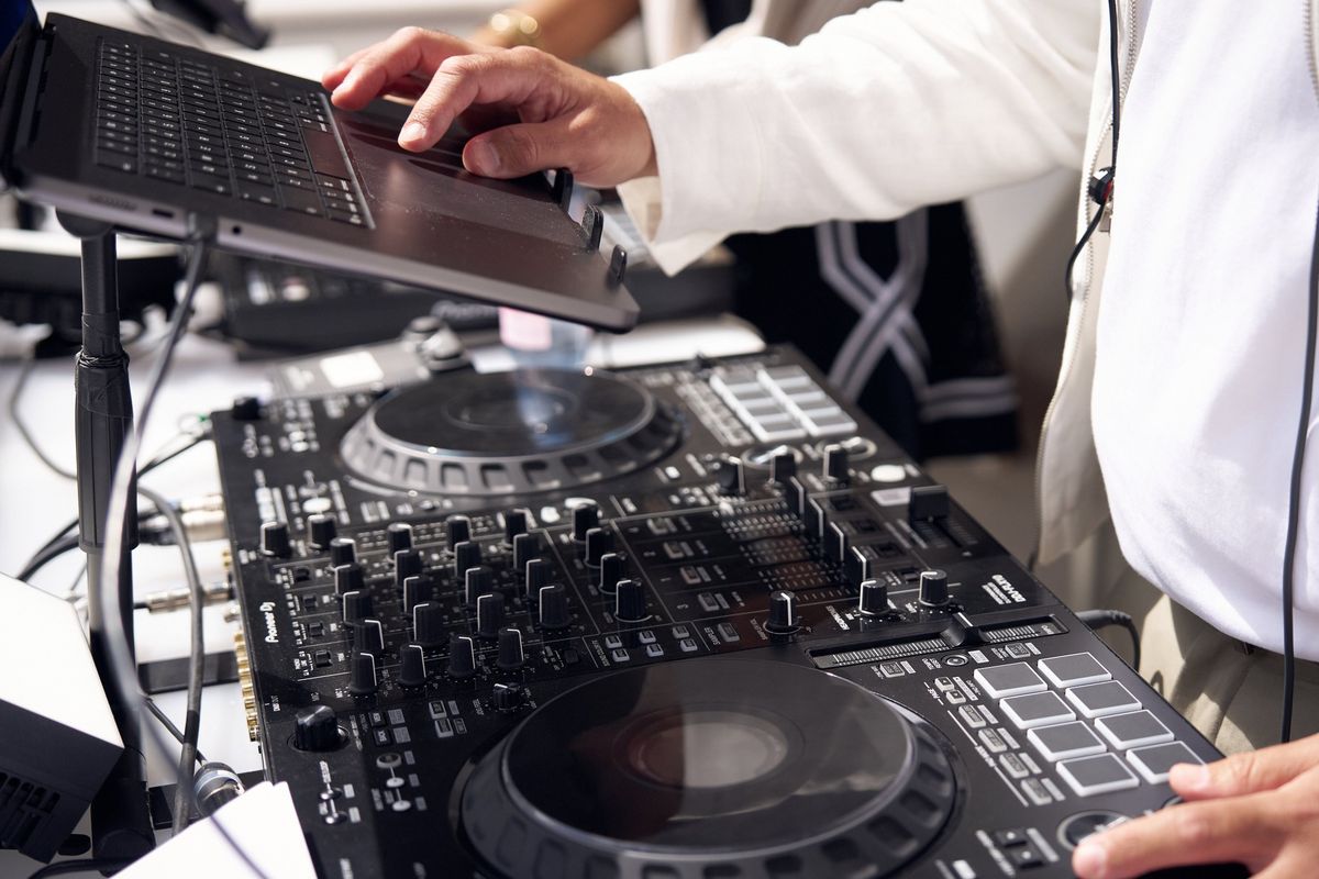DJ Mode's hands on a Pioneer DJ controller and laptop stand