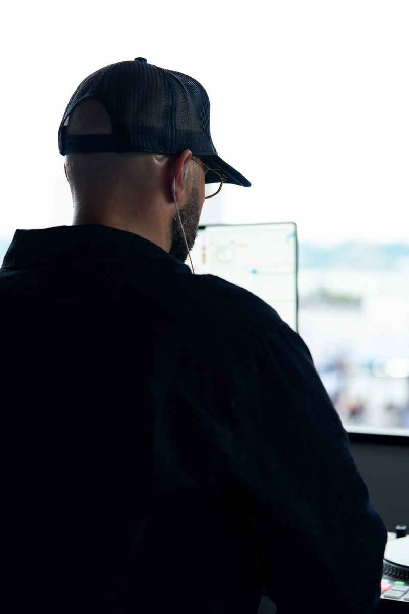 Silhouette of DJ Mode from behind at the decks by a bright window
