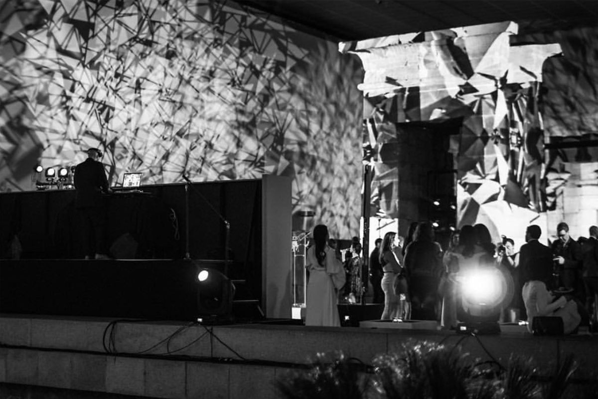 DJ Mode performing on a stage with a crowd in black and white