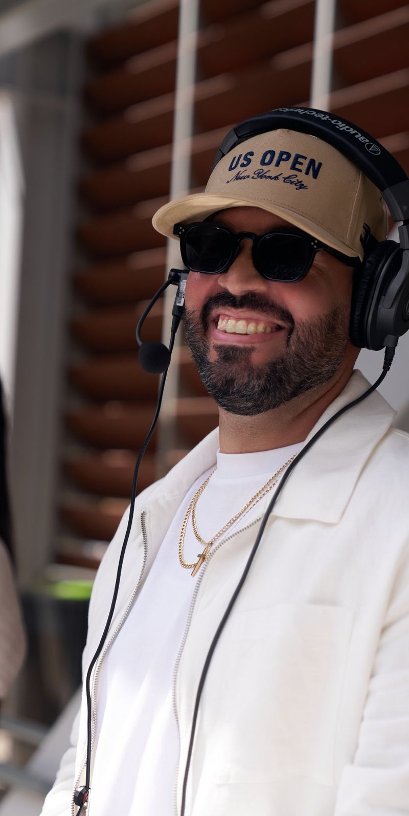 DJ Mode grinning in a US Open cap, headphones and headset mic