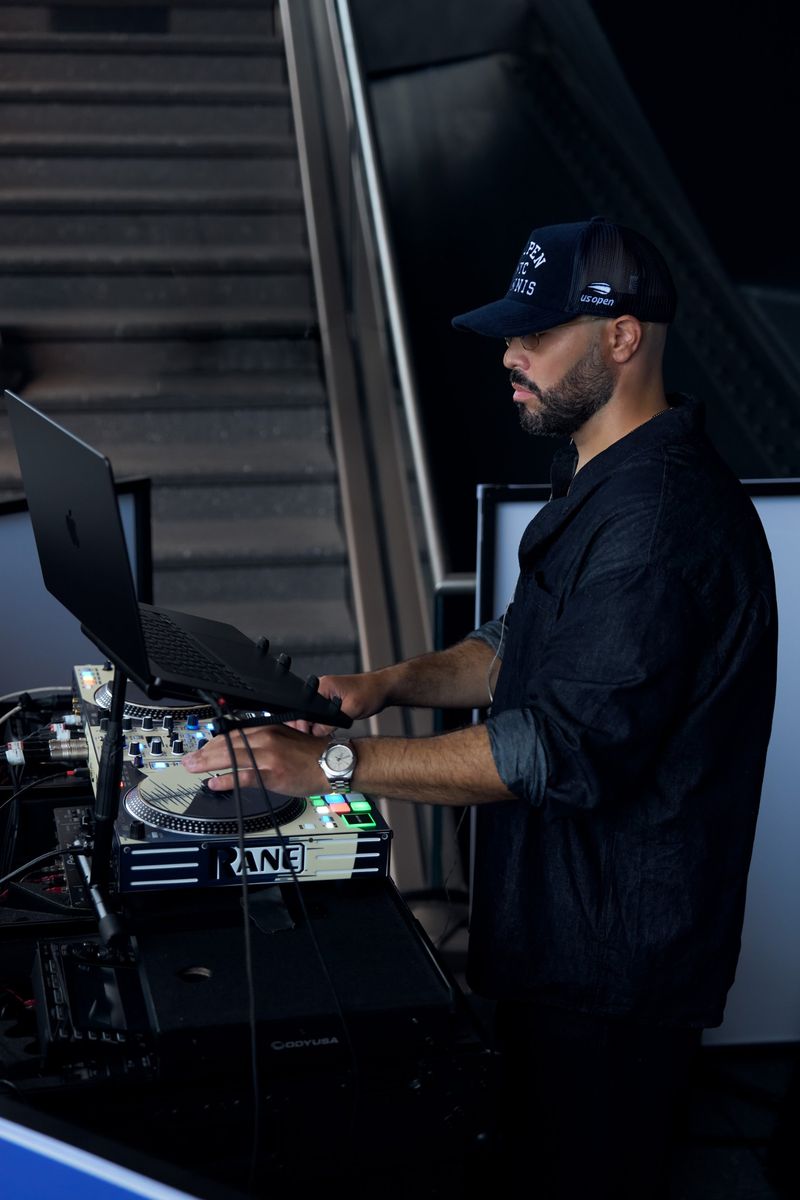DJ Mode in profile at the Rane decks in a US Open NYC Tennis cap